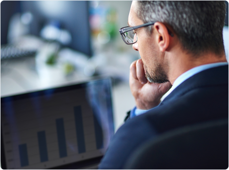 Executive in glasses studying a bar chart on a laptop screen