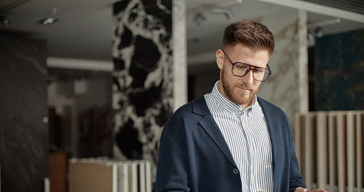 Young founder in glasses looking down at a phone in a modern office